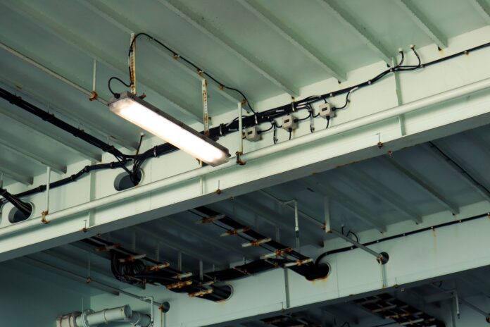 Przemysłowa lampa sufitowa i okablowanie w hali magazynowej e-commerce Przemysłowa lampa sufitowa i okablowanie w hali magazynowej e-commerce