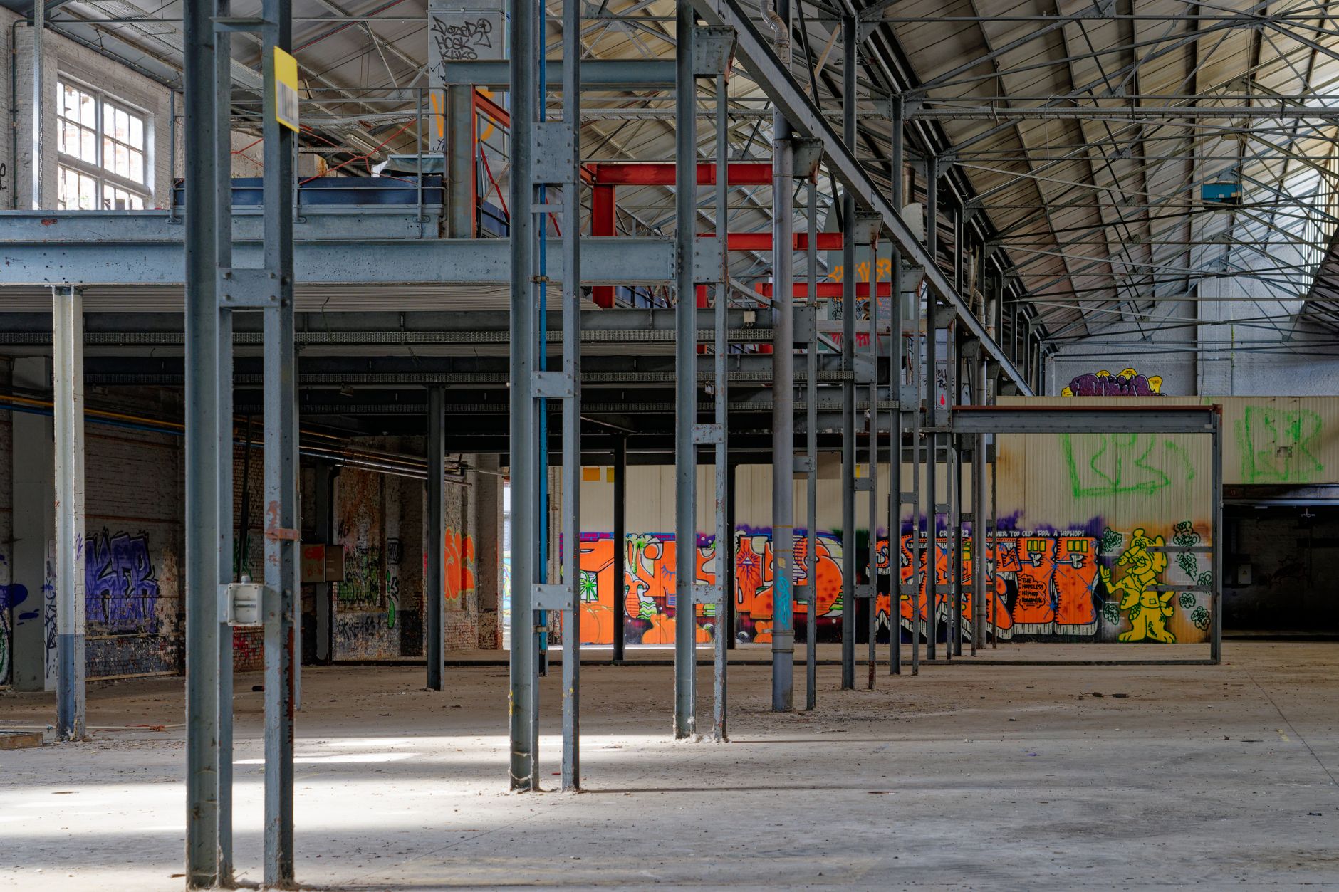 Wnętrze opuszczonego magazynu pokryte graffiti i industrialną konstrukcją